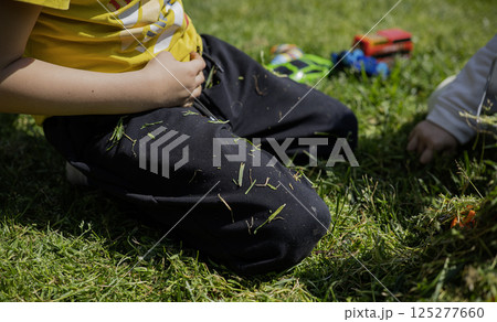 A child plays with toy cars on the lawn in the sunny day A child plays with toy cars on the lawn in the sunny day 125277660