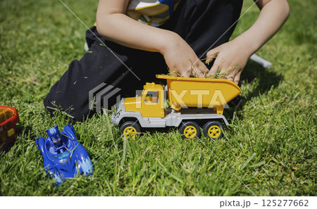A child plays with toy cars on the lawn in the sunny day 125277662