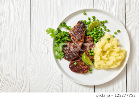 grilled beef cutlets with potato mash, green peas 125277755