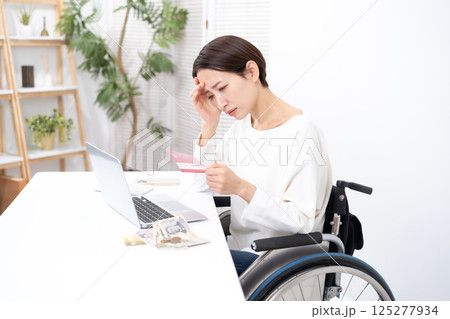 車椅子の女性　お金　通帳　悩む 125277934