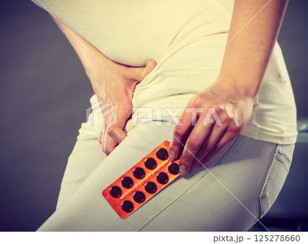 Woman suffer from belly pain holds pills 125278660
