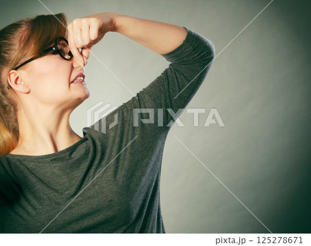 Nerdy girl holding nose. 125278671