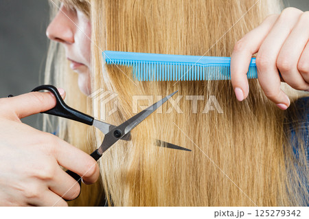 Girl is cutting her hair down. 125279342