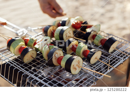 A young man in a summer casual outfit is having a barbecue on beach. A young man in a summer casual outfit is having a barbecue on beach. 125280222