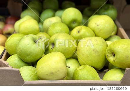 Box filled with fresh natural bio organic green apples placed on counter in local food market. Close-up 125280630