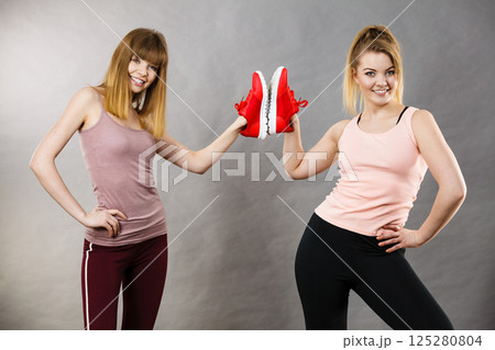 Two women presenting sportswear trainers shoes 125280804