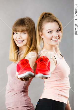 Two women presenting sportswear trainers shoes 125280805