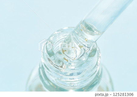 Close-up of clear serum with gold flakes in glass bottle and dropper on light 125281306