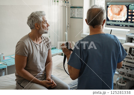 Doctor explaining colonoscopy results to patient using monitor images. Doctor explaining colonoscopy results to patient using monitor images. 125281338