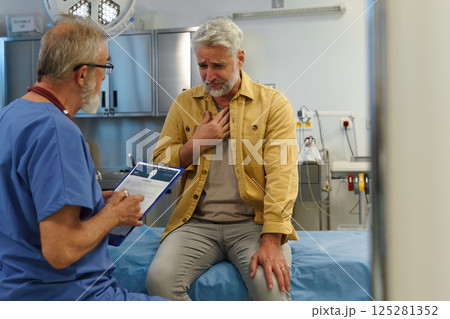 Patient sitting on examination table, describing chest pain to doctor. Patient sitting on examination table, describing chest pain to doctor. 125281352