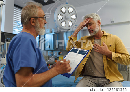 Patient sitting on examination table, describing symptoms to doctor. 125281353