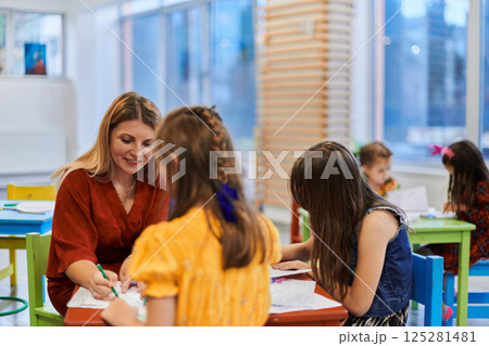 Creative kids during an art class in a daycare center or elementary school classroom drawing with female teacher. Creative kids during an art class in a daycare center or elementary school classroom drawing with female teacher. 125281481