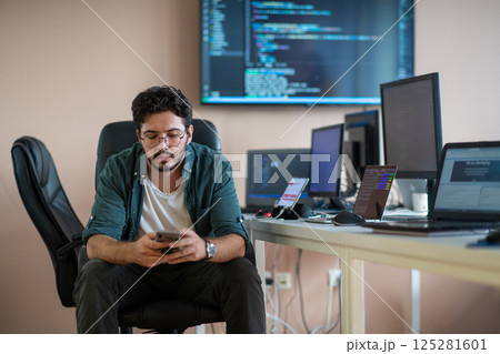 A programmer diligently testing smartphone applications A programmer diligently testing smartphone applications 125281601