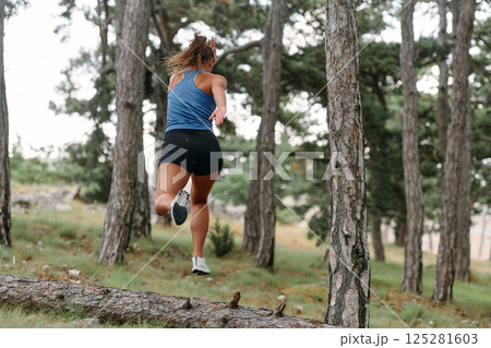 Fearless Woman Conquering Wooden Obstacles in the Dangerous Forest Terrain. Fearless Woman Conquering Wooden Obstacles in the Dangerous Forest Terrain. 125281603