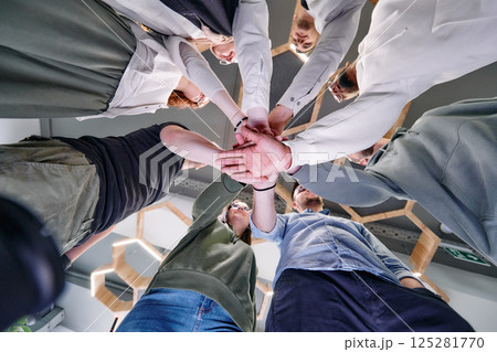 A group of young businessmen offer their hands together, symbolizing togetherness in the business world 125281770