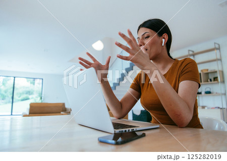 Woman sitting in living room using laptop looking at cam talk by video call with business friend relatives, head shot. Job interview answering questions Woman sitting in living room using laptop looking at cam talk by video call with business friend relatives, head shot. Job interview answering questions 125282019