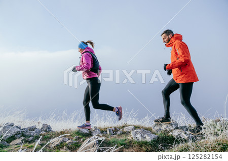 Trail running couple man and woman running on a mountain path 125282154