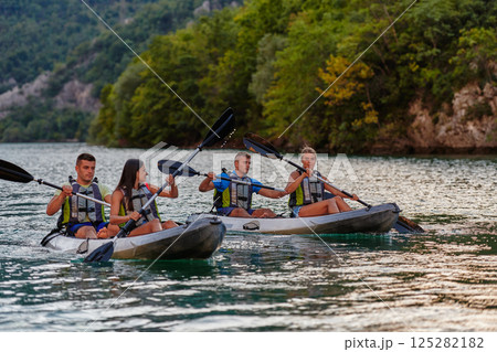 A group of friends enjoying having fun and kayaking while exploring the calm river, surrounding forest and large natural river canyons 125282182