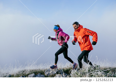 Trail running couple man and woman running on a mountain path Trail running couple man and woman running on a mountain path 125282213