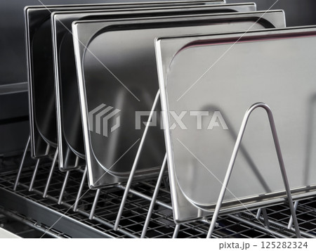 Stainless steel trays arranged neatly on a rack in a modern kitchen setting during daytime Stainless steel trays arranged neatly on a rack in a modern kitchen setting during daytime 125282324