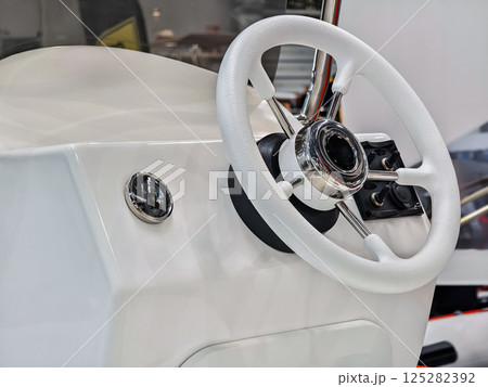 Boat steering wheel console with shiny chrome accents and clean white design showcasing marine equipment and craftsmanship 125282392