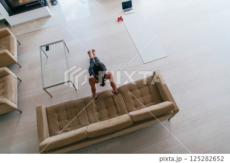 Training At Home. Sporty man doing the training while watching an online tutorial on a laptop, exercising in the living room, free space. 125282652