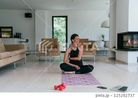 Young Beautiful Female Exercising, Stretching and Practising Yoga with Trainer via Video Call Conference in Bright Sunny House. Healthy Lifestyle, Wellbeing and Mindfulness Concept 125282737
