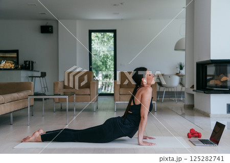 Young Beautiful Female Exercising, Stretching and Practising Yoga with Trainer via Video Call Conference in Bright Sunny House. Healthy Lifestyle, Wellbeing and Mindfulness Concept 125282741