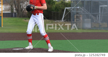 High School Baseball Player on the Pitcher's Mound Preparing to Throw 125282749