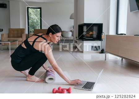 Young Beautiful Female Woman with Trainer via Video Call Conference in Bright Sunny House. Healthy Lifestyle, Wellbeing and Mindfulness Concept. Young Beautiful Female Woman with Trainer via Video Call Conference in Bright Sunny House. Healthy Lifestyle, Wellbeing and Mindfulness Concept. 125282824
