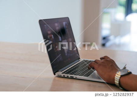 Photo of a laptop with modern headphones on a wooden table in a house with a modern interior. Photo of a laptop with modern headphones on a wooden table in a house with a modern interior. 125282937
