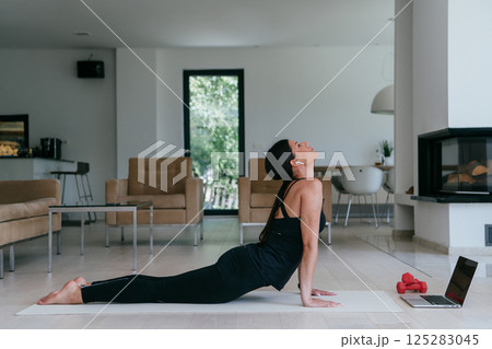 Young Beautiful Female Exercising, Stretching and Practising Yoga with Trainer via Video Call Conference in Bright Sunny House. Healthy Lifestyle, Wellbeing and Mindfulness Concept 125283045
