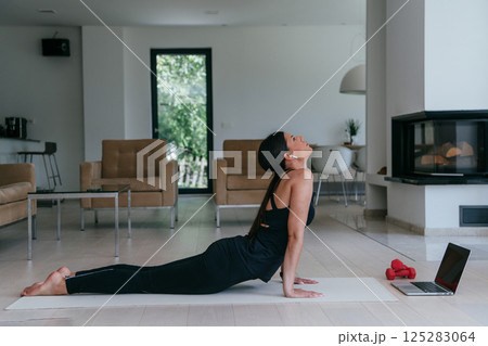 Young Beautiful Female Exercising, Stretching and Practising Yoga with Trainer via Video Call Conference in Bright Sunny House. Healthy Lifestyle, Wellbeing and Mindfulness Concept Young Beautiful Female Exercising, Stretching and Practising Yoga with Trainer via Video Call Conference in Bright Sunny House. Healthy Lifestyle, Wellbeing and Mindfulness Concept 125283064