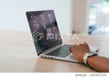 Photo of a laptop with modern headphones on a wooden table in a house with a modern interior.  125283138