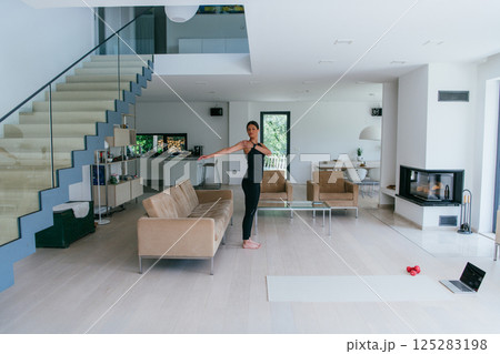 Young Beautiful Female Exercising, Stretching and Practising Yoga with Trainer via Video Call Conference in Bright Sunny House. Healthy Lifestyle, Wellbeing and Mindfulness Concept 125283198