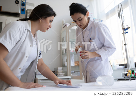 Two nurses in a hospital laboratory are carefully inspecting and preparing medications for patients and hospital use. 125283299