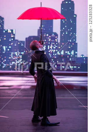 Mysterious Clown Performer with Red Umbrella in Urban Nightscape. 125283328