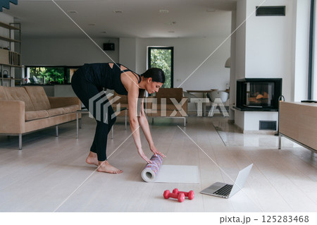 Young Beautiful Female Exercising, Stretching and Practising Yoga with Trainer via Video Call Conference in Bright Sunny House. Healthy Lifestyle, Wellbeing and Mindfulness Concept. Young Beautiful Female Exercising, Stretching and Practising Yoga with Trainer via Video Call Conference in Bright Sunny House. Healthy Lifestyle, Wellbeing and Mindfulness Concept. 125283468