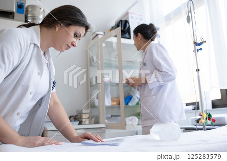 Two nurses in a hospital laboratory are carefully inspecting and preparing medications for patients and hospital use. Two nurses in a hospital laboratory are carefully inspecting and preparing medications for patients and hospital use. 125283579