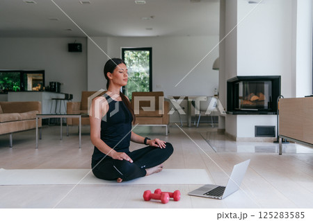 Young Beautiful Female Exercising, Stretching and Practising Yoga with Trainer via Video Call Conference in Bright Sunny House. Healthy Lifestyle, Wellbeing and Mindfulness Concept. 125283585