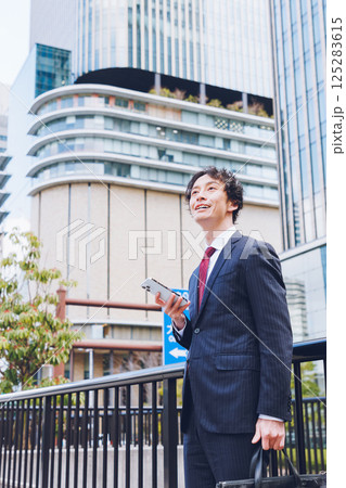 オフィス街でスマートフォンを使う男性 オフィス街でスマートフォンを使う男性 125283615