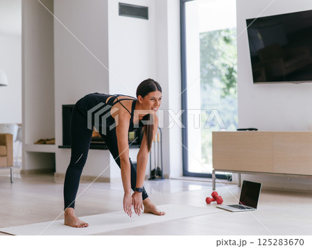 Young Beautiful Female Exercising, Stretching and Practising Yoga with Trainer via Video Call Conference in Bright Sunny House. Healthy Lifestyle, Wellbeing and Mindfulness Concept 125283670