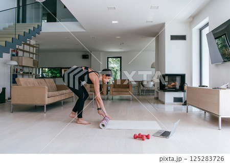 Young Beautiful Female Exercising, Stretching and Practising Yoga with Trainer via Video Call Conference in Bright Sunny House. Healthy Lifestyle, Wellbeing and Mindfulness Concept. 125283726