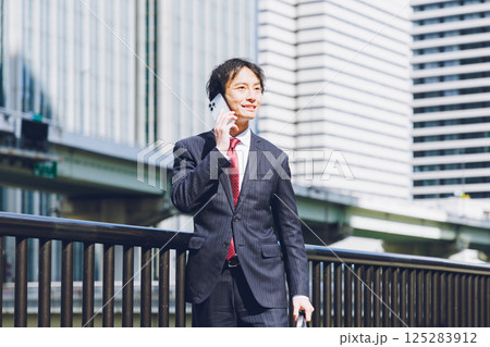 オフィス街でスマートフォンを使う男性 125283912