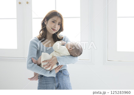 赤ちゃんを抱っこする可愛いママ 125283960