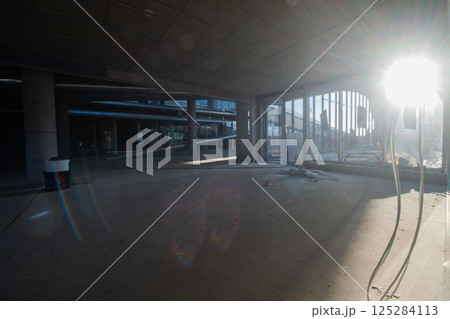 A captivating view of a modern business building under construction, showcasing its raw industrial interior with exposed steel beams and concrete walls bathed in the warm, golden hues of a sunset 125284113