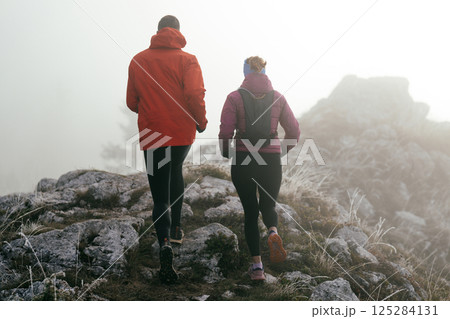 Trail running couple man and woman running on a mountain path Trail running couple man and woman running on a mountain path 125284131