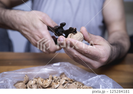 The man is cracking walnuts at home The man is cracking walnuts at home 125284181