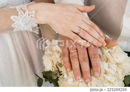 Intimate Close-Up of Newlywed's Hands Displaying Wedding Rings on a Bouquet Backdrop Signifying Love and Commitment 182 Intimate Close-Up of Newlywed's Hands Displaying Wedding Rings on a Bouquet Backdrop Signifying Love and Commitment 182 125284293