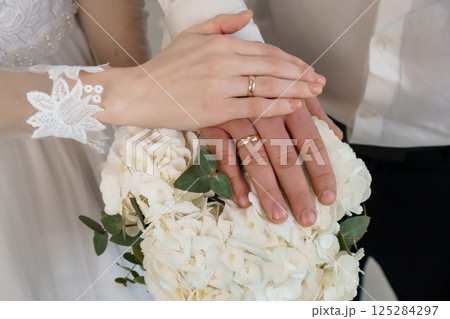Couple s Hands with Wedding Rings and Bouquet - A Symbol of Love, Commitment, and New Beginning in a Stylish Celebration of Marriage Couple s Hands with Wedding Rings and Bouquet - A Symbol of Love, Commitment, and New Beginning in a Stylish Celebration of Marriage 125284297